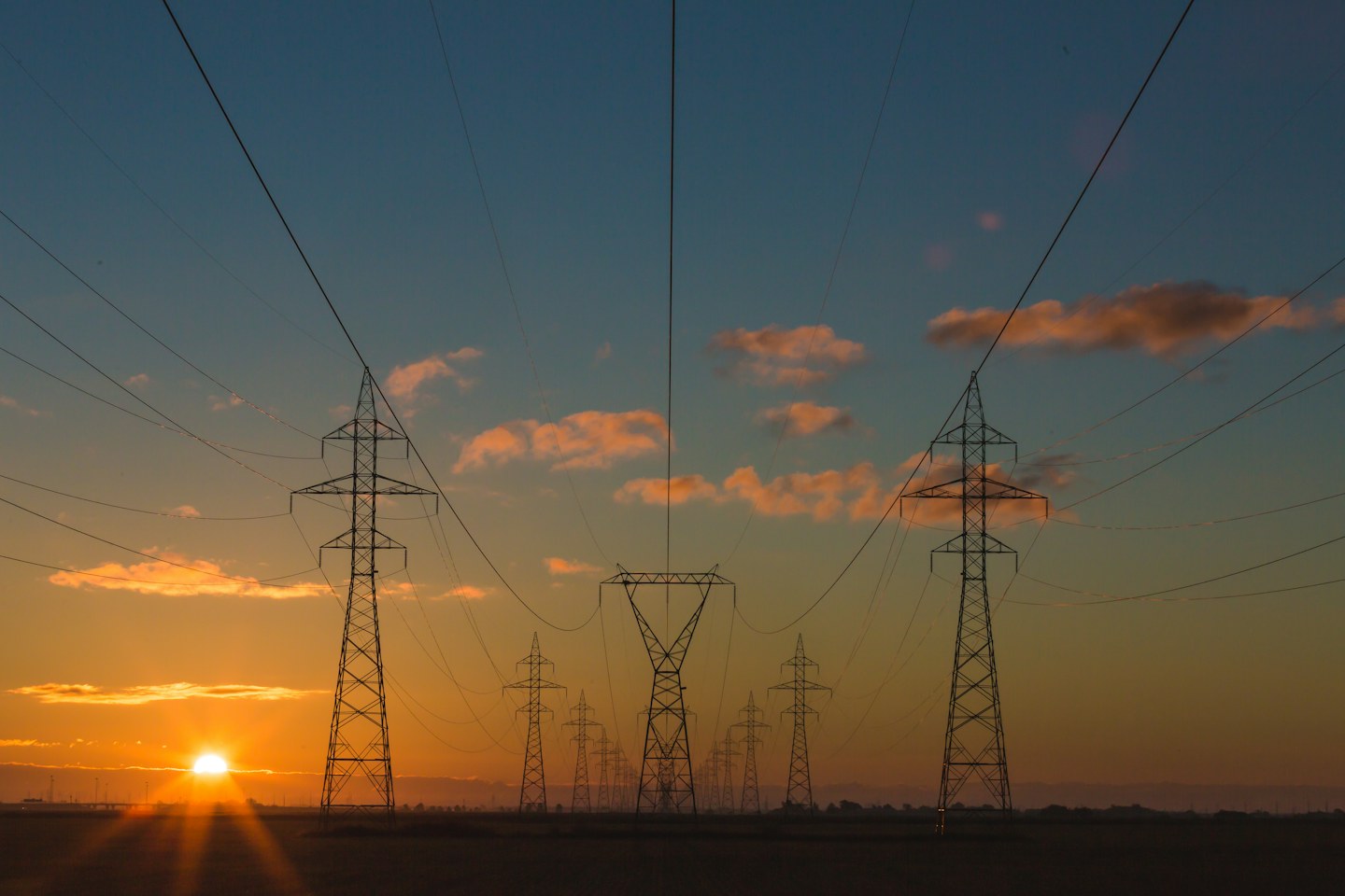 Electricity transmission pylons silhouetted against a sunset